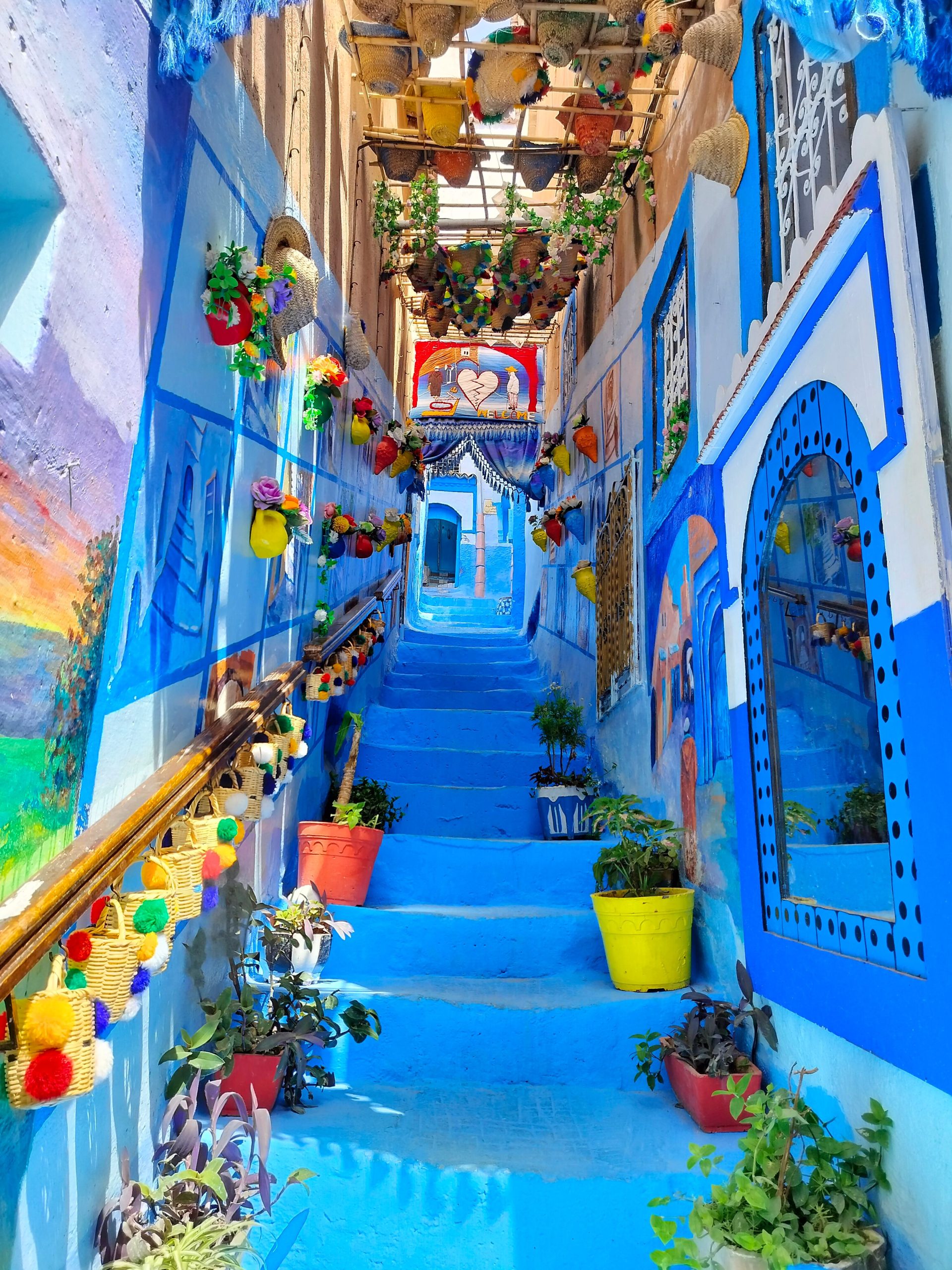 A blue painted staircase in the Chefchaouen medina with plants and baskets