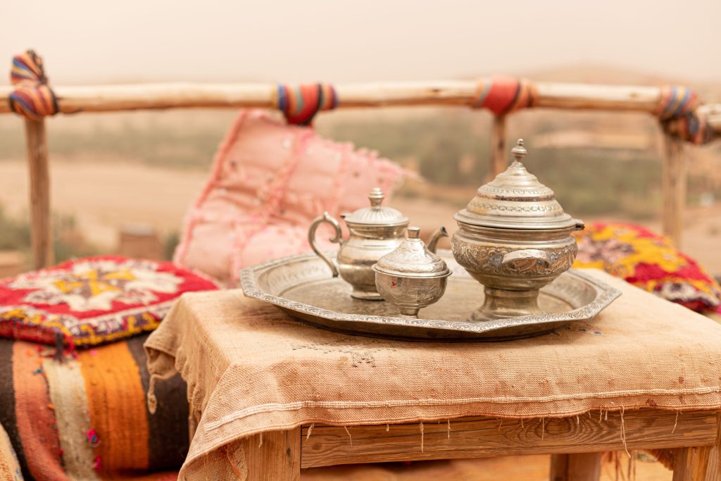 Moroccan silver teapot and glasses set on the sand at sunset in the Sahara
