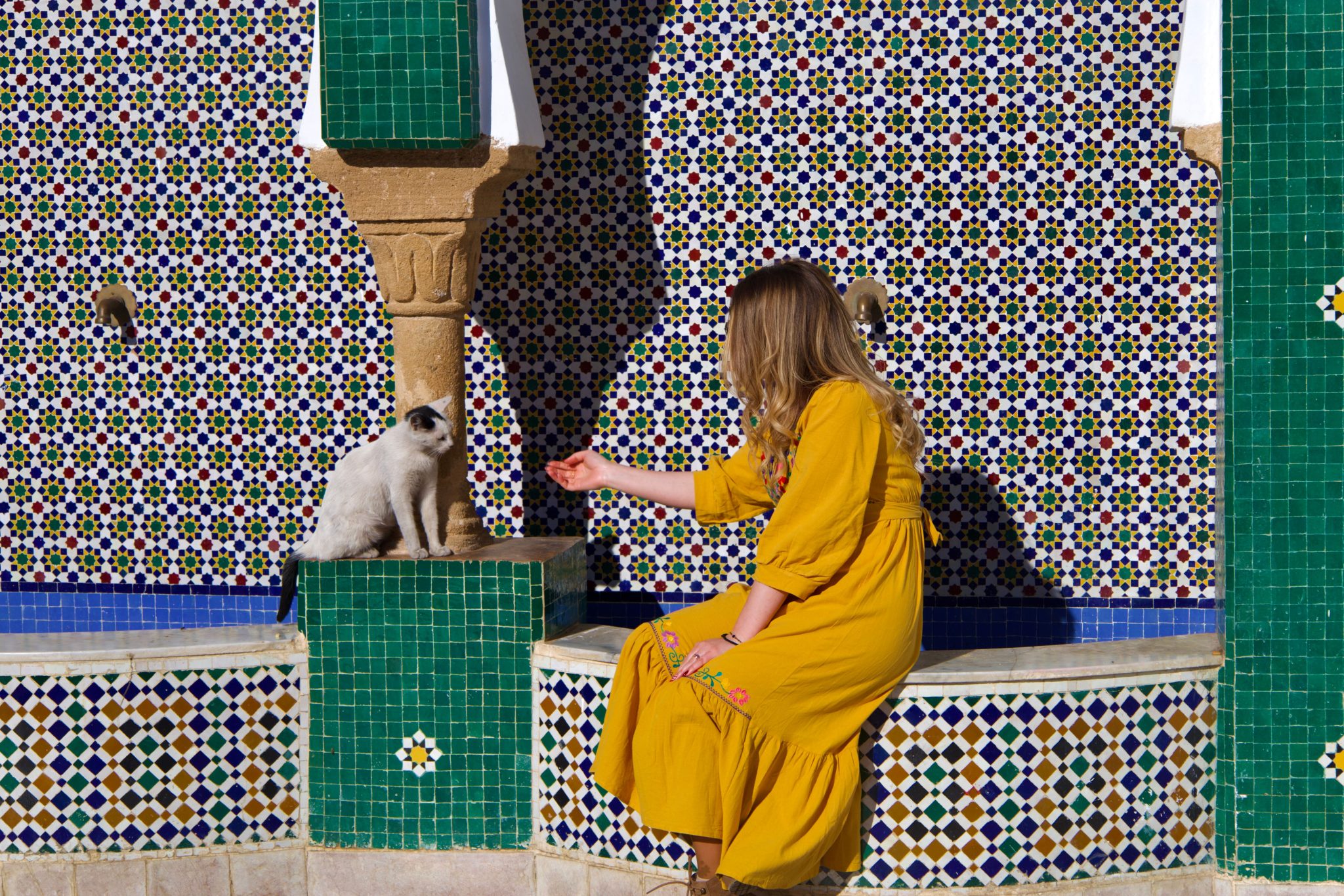 A woman travelling in Morocco beside a tiled courtyard fountain