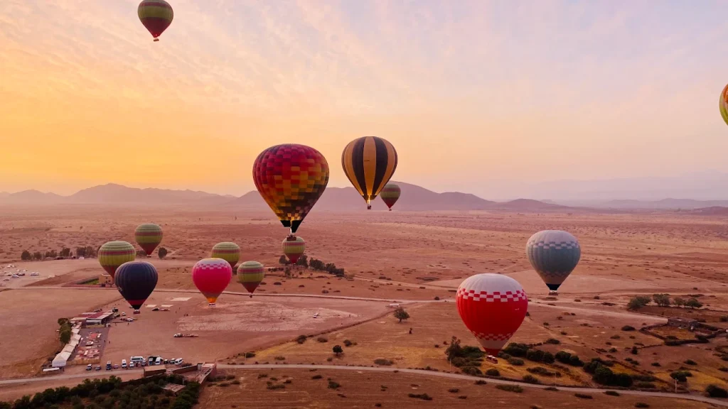 A hot air balloon rising over the plain outside Marrakech at dawn
